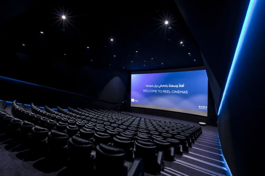 An empty modern cinema with a large screen and comfortable seating.